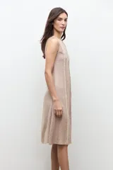 Vestido midi sin mangas de lino color tostado, con diseño de paneles con detalles desflecados en las costuras y un cinturón fino ajustable con hebilla metálica.