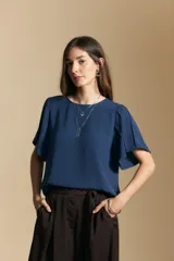 Top de color azul, con escote redondo a la base y mangas cortas amplias con caída fluida. Presenta una silueta relajada y un diseño minimalista.