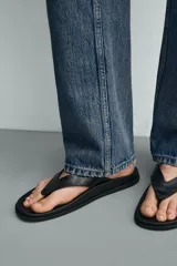 Sandalias de dedo color negro con suela plana y tiras anchas en el empeine con diseño de chancleta.