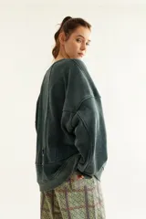 Buzo oversize de corte unisex, color rojo con efecto desgastado (acid wash), confeccionado en algodón con interior de polar. Presenta costuras frontales decorativas, hombros caídos, mangas largas con puños elastizados, rib en el cuello y el ruedo, y un pequeño logo bordado en el pecho.
