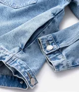 Campera de jean en color azul con efecto desgastado, cuello clásico, cierre frontal con botones metálicos y dos bolsillos con solapa en el pecho.