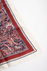 Bandana cuadrada con estampado paisley en tonos bordó, azul marino y blanco, con bordes en tono crudo y marco decorativo.