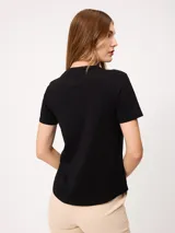 Remera básica de manga corta y cuello en V, de color negro, con un pequeño detalle bordado en el pecho.
