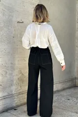 Pantalón de jean color beige, de corte ancho, recto y de tiro alto. Tiene elástico y pinzas en la pretina.