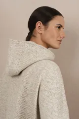 Capa con capucha, cierre frontal completo y bolsillos laterales con cierre. Presenta un diseño amplio y descontracturado, confeccionada en lana fina sin teñir.