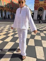 Camisa blanca de broderie con cuello camisero, mangas largas y cierre frontal con botones.