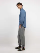 Camisa de hombre color azul, con cuello buttondown, cierre frontal con botones y logo bordado en el pecho. Presenta un acabado vintage logrado mediante el proceso de teñido en prenda.