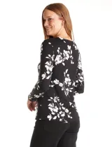 Remera de modal estampada con flores blancas sobre fondo negro, de manga larga y cuello redondo.