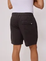 Bermuda de corte recto en color beige, confeccionada en una mezcla de algodón, lino y poliéster. Presenta cintura elástica con cordón ajustable, bolsillos laterales y una pequeña etiqueta decorativa en el ruedo.