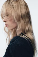 Jersey de punto color azul marino con escote en pico y manga larga. Presenta un diseño texturizado con aplicaciones de flores en relieve del mismo tejido en el cuello y el ruedo.