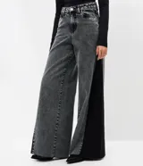 Pantalón wide leg de jean azul con diseño de recorte lateral en tono contrastante. Presenta cintura mediana con trabillas, cierre tradicional y bolsillos funcionales.