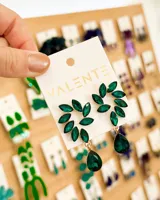 Par de aros colgantes con forma de hojas y gota, con incrustaciones de cristal color esmeralda y engarce dorado.