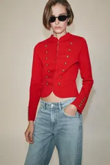 Chaquetas de cuello redondo y manga larga, de color rojo. Cuenta con detalle de botones dorados frontales y en los puños, con cierre delantero con corchetes ocultos.