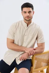 Camisa de lino y algodón color beige, de manga corta, con cuello mao y bolsillo frontal en el pecho.