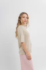 Buzo de tejido abierto color beige claro, de calce oversize con mangas 3/4 y cuello redondo. Presenta terminaciones acanaladas en puños y cintura.