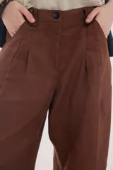 Pantalón de lino marrón de tiro medio, con calce holgado y diseño de piernas amplias. Cuenta con bolsillos traseros, trabillas para cinto y un pin bordado en contraste.