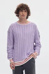 Buzo de punto blanco crudo con tejido de ochos y diseño regular. Cuenta con cuello redondo, puños y ruedo acanalados en color negro con líneas blancas en contraste.