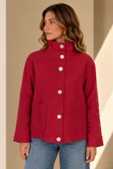 Campera de lino color rojo, con cuello alto, cierre frontal con grandes botones de nácar y bolsillos frontales parche.