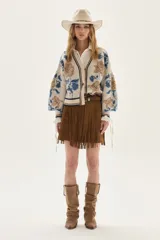 Cardigan de tejido de punto color crudo con diseño de jacquard floreado en tonos azules y marrones. Presenta cuello en V, cierre frontal con botones y ribetes a rayas en cuello, puños y bajo.