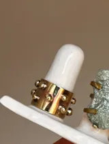 Anillo ancho de bronce color dorado con tachas redondas.