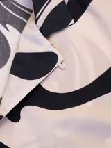 Camisa de manga corta con cuello tipo camp y estampado abstracto en tonos beige y negro.