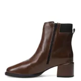 Botas de cuero color marrón con acabado brillante, diseño de caña media con elástico lateral y detalle de tira con hebilla metálica en el tobillo. Cuenta con taco cuadrado y suela de goma.