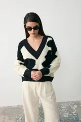 Sweater de tejido bouclé con diseño de animal print abstracto en blanco y negro, cuello en V y corte holgado.