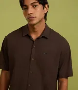 Camisa de corte relajado para hombre, confeccionada en una mezcla de cáñamo y algodón. Presenta cuello inglés, manga corta, cierre frontal con botones y un bolsillo en el pecho con una pequeña etiqueta aplicada.