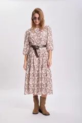 Vestido largo de corte holgado con diseño de paneles escalonados, estampado floral en tonos marrón y beige, cuello redondo y mangas tres cuartos abullonadas.