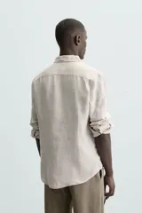 Camisa de corte regular fit confeccionada en tejido de lino, con cuello solapa, manga larga con puños abotonados y cierre frontal de botones.