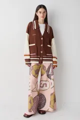 Pantalon de corte wide leg y tiro alto, color rosado con estampado de motivos deportivos como pelotas de fútbol y raquetas de tenis. Cuenta con cierre frontal con botón y bolsillos laterales.