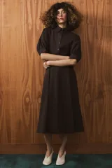 Vestido midi de algodón con cuello solapa, cierre frontal con botones y mangas cortas abullonadas con puños. Presenta un diseño evasé con bolsillos laterales ocultos y elástico en la espalda.