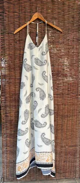 Vestido largo de seda color crudo con estampado de cachemir en negro, musculosa de tirantes finos y espalda semi descubierta.