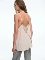 Top lencero de tirantes finos, color blanco, con escote en V decorado con encaje. Presenta una silueta holgada y liviana.