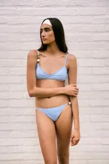 Conjunto de bikini celeste con corpiño triangular con detalle de piedras en los breteles y espalda para atar, y bombacha semivedetina regulable con detalle de piedras en uno de los breteles laterales.