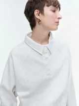 Buzo de cuello polo con escote abotonado, manga larga raglán y puños acanalados. Confeccionado en tejido suave y confortable.