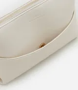 Cartera pequeña de hombro confeccionada en poliuretano color crema, con textura acolchada tipo diamante en la parte inferior y cierre superior. Incluye correa ajustable con herrajes dorados.