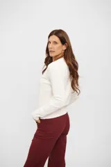 Cardigan de tejido de punto color blanco hueso, de manga larga y escote redondo, con cierre frontal de botones.