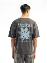 Remera blanca de corte oversize con cuello redondo y manga corta. Presenta un pequeño estampado frontal de un envase de bebida con texto en japonés y una flor.