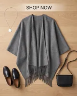 Poncho de abrigo color gris con flecos en el borde inferior y diseño envolvente.