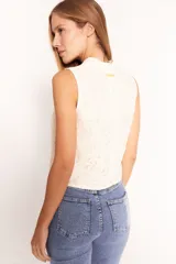Chaleco de encaje color crema con cuello alto y sin mangas.