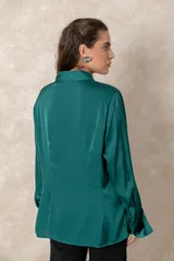 Camisa de seda con acabado satinado, de corte holgado y manga larga con puños anchos. Presenta cuello clásico y cierre frontal con botones al tono.