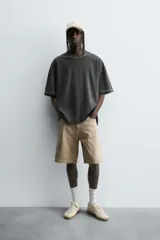 Bermuda de denim de algodón, color verde claro lavado, de corte recto y tiro medio. Presenta cinco bolsillos y cierre frontal con cremallera y botón.