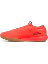 Championes de fútbol sala Under Armour Magnetico Select 4, color naranja vibrante con suela de goma color caramelo. Presenta un diseño de ajuste tipo calcetín con cuello textil, parte superior de piel sintética suave y logo de la marca con detalles gráficos en el lateral.