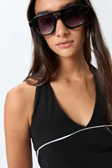 Top halter negro con escote en V y detalle de vivo blanco horizontal. Presenta un diseño ajustado al cuerpo y espalda descubierta con tiras regulables.