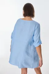 Vestido corto color beige de lino, con cuello redondo, corte oversize y mangas 3/4 con botón. Presenta bolsillos laterales.