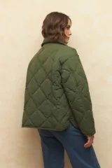 Campera capitoneada negra con botones veteados, bolsillos laterales de solapa y forro de satén con estampado animal print.