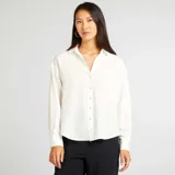 Camisa blanca de corte holgado con cuello clásico y mangas largas.