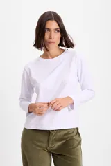 Remera de manga larga color blanco, con cuello redondo y corte holgado. Presenta un pequeño bordado en el centro del pecho.