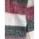 Bufanda rectangular de tejido grueso con diseño de cuadros en tonos azul, naranja, gris y beige, terminada con flecos en los extremos.
